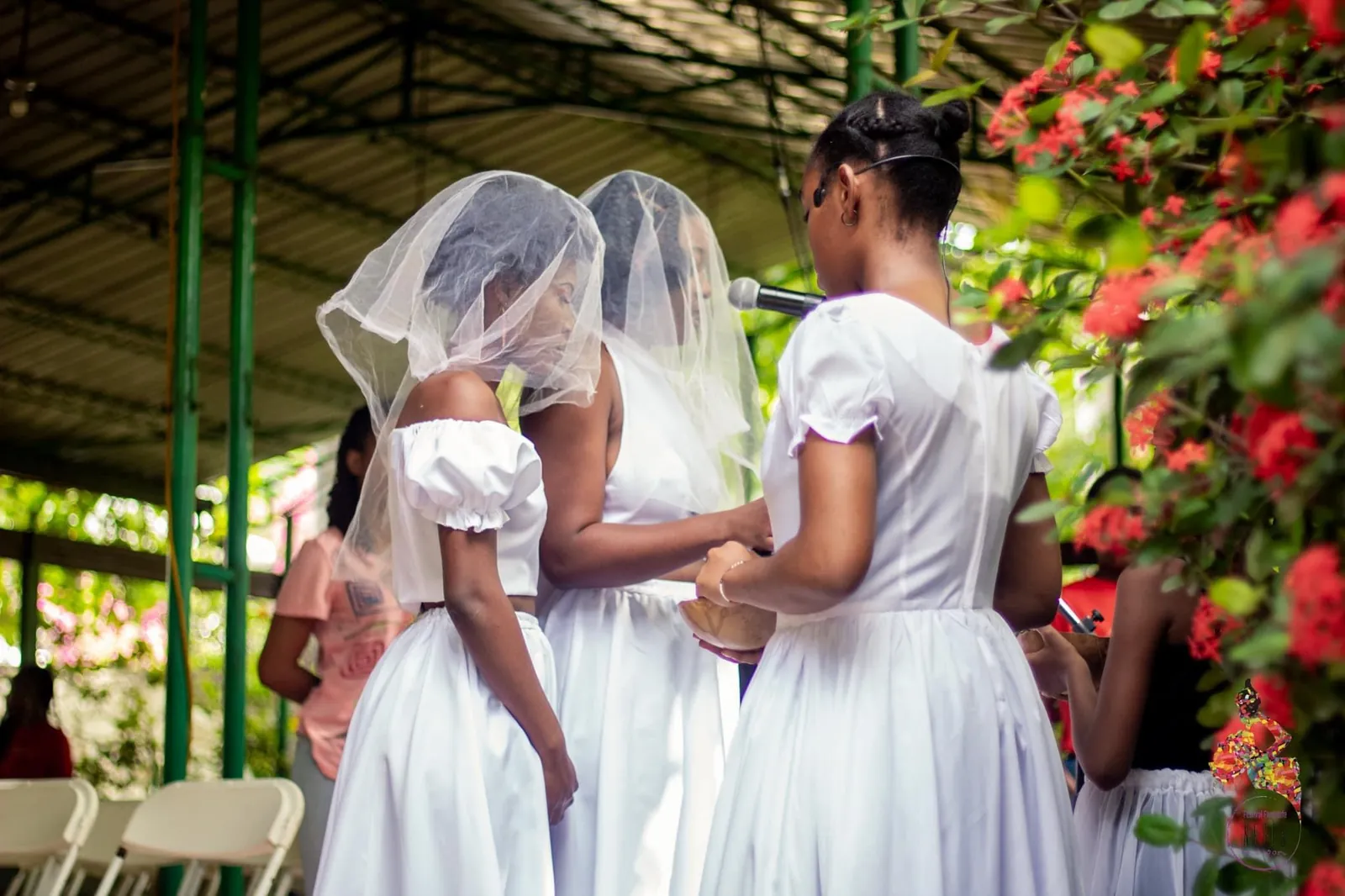Performers in white dresses and veils in a garden