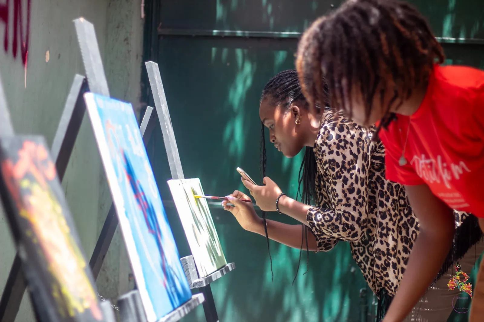 Two young women painting on canvases