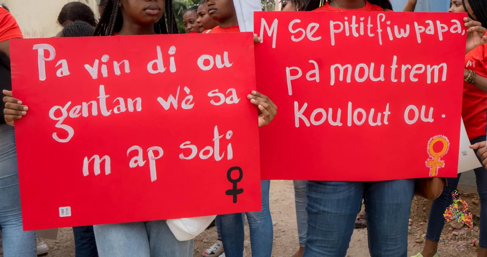 Two red placards in Haitian Creole held up in the street