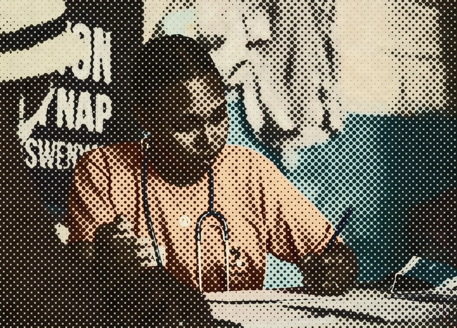 A NÈGÈS MAWON member in an orange shirt writing at a table, a stethoscope around her neck